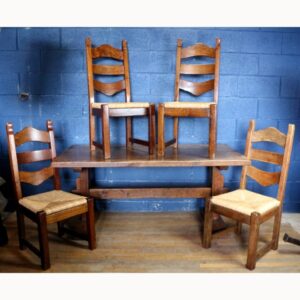 A Rustic Solid Oak Trestle Dining Table along with Set of Four Ladder Back Rush Seat Dining Chairs