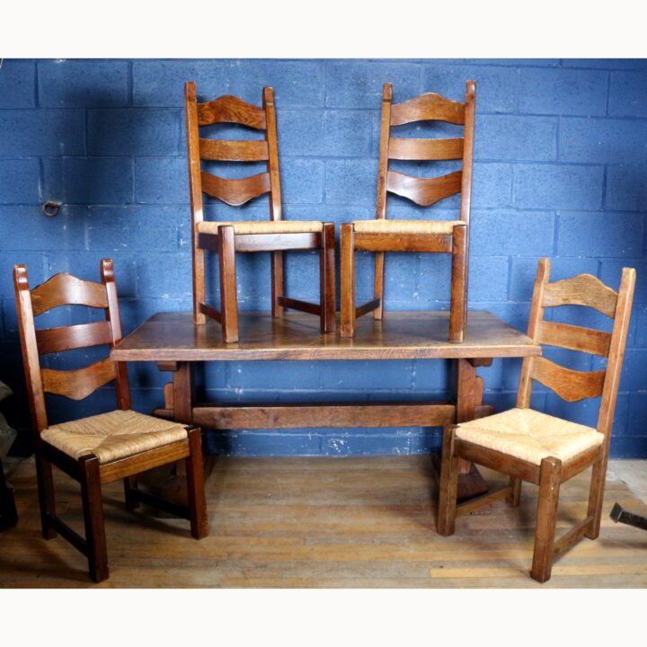 A Rustic Solid Oak Trestle Dining Table along with Set of Four Ladder Back Rush Seat Dining Chairs